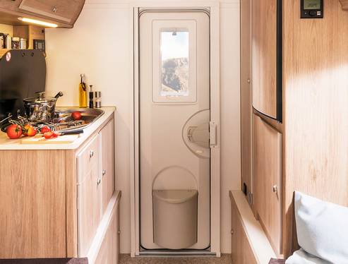 Dörr med myggnät, sophink och fönster med jalusi