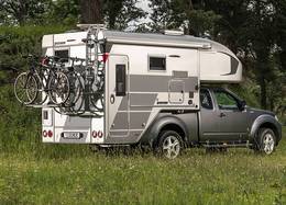 Tischer pickup camper TRAIL 260SD på en silverfärgad Nissan Navara med omtypning och höjda vikter stående i en skog