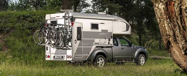 Tischer pickup camper TRAIL 260SD på en silverfärgad Nissan Navara med omtypning och höjda vikter stående i en skog 