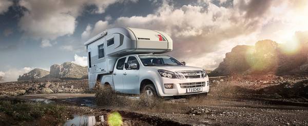 Vit Isuzu D-Max med Tischer pickup camper TRAIL 230S brakande genom bergens kvällsljus