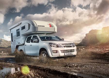 Vit Isuzu D-Max med Tischer pickup camper TRAIL 230S brakande genom bergens kvällsljus