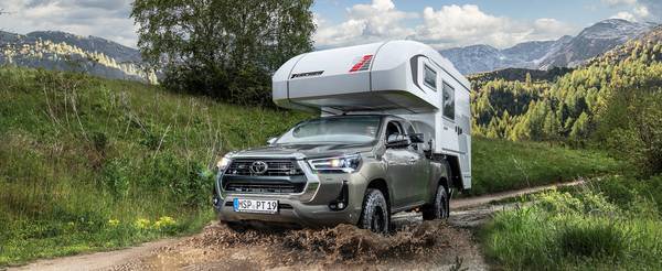 Toyota Hilux med Tischer pickup camper TRAIL 260S brakar genom en gyttjepöl i Alperna