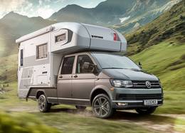 VW Transporter med Tischer camper TRAIL 280S brakar genom ett grönt berglandskap